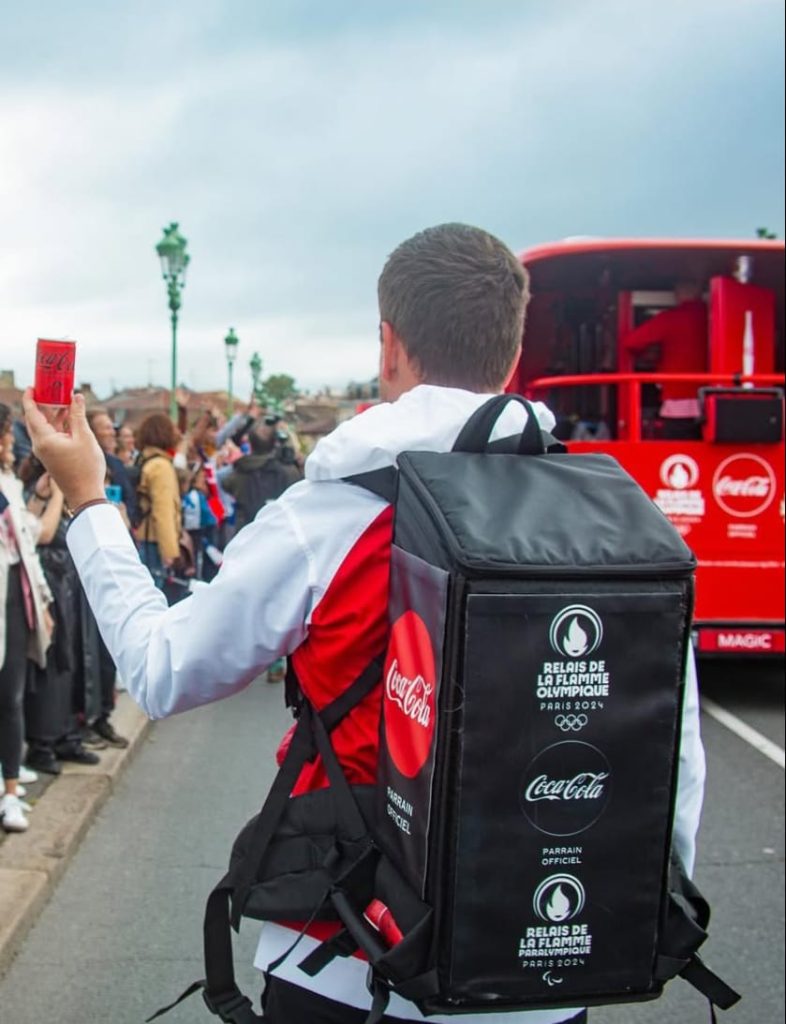 Opérateur portant un sac isotherme Coca-Cola de type Soft Bag lors du Relais de la Flamme Olympique pour la distribution mobile de boissons.